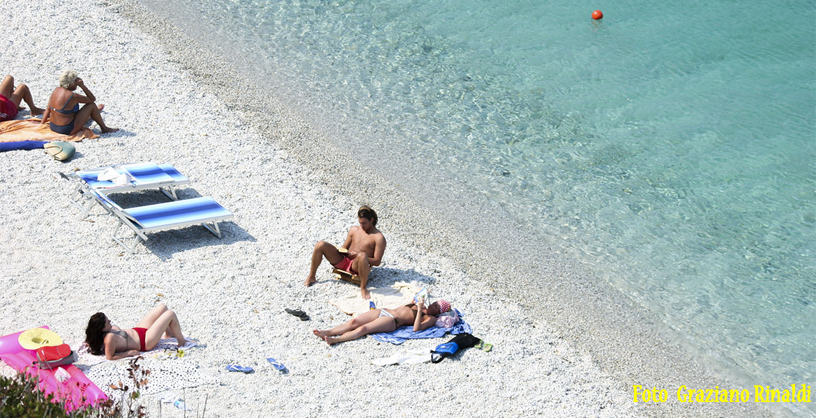 Spiagge Isola d'Elba_Spiaggia di Sansone_turista che legge il giornale sulla battigia in piano sole